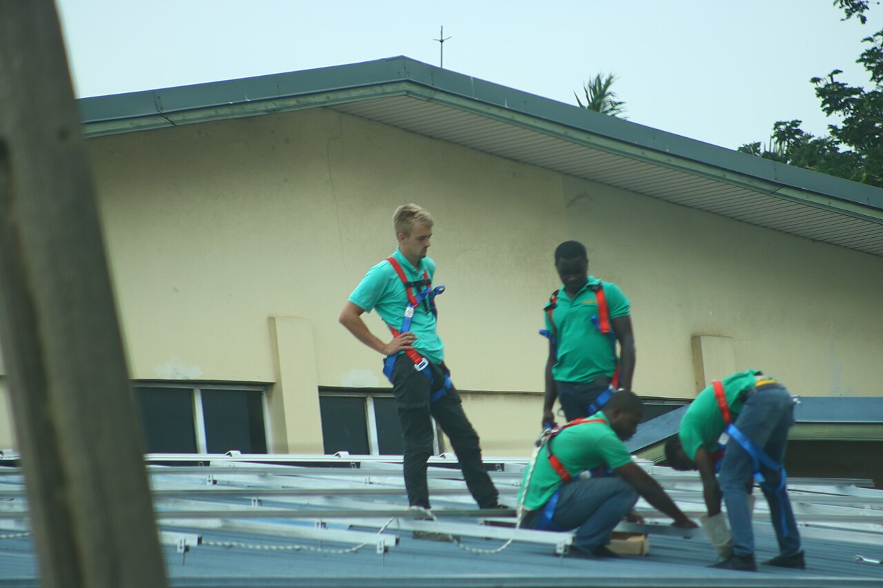 Equipo técnico instalando paneles solares con arnés de seguridad